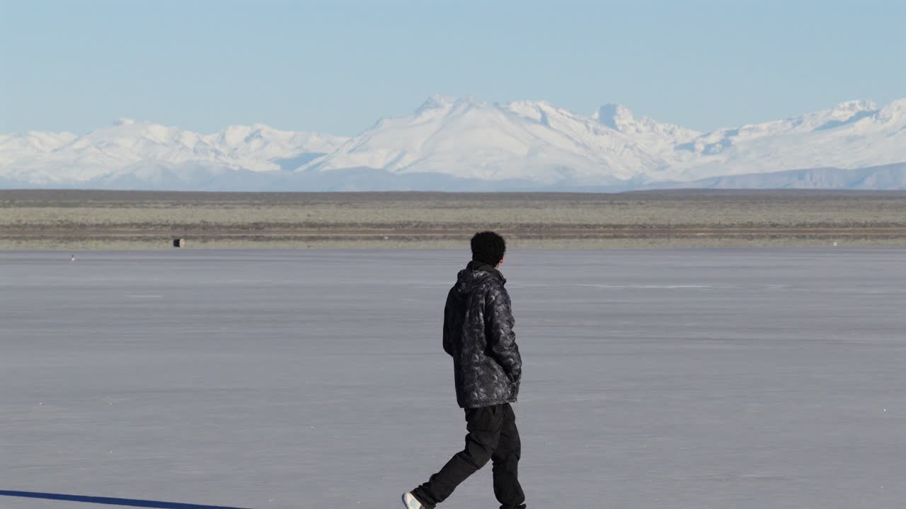 Hiker in winter cloth crossing barren salt desert in Argentina, adventure and freedom