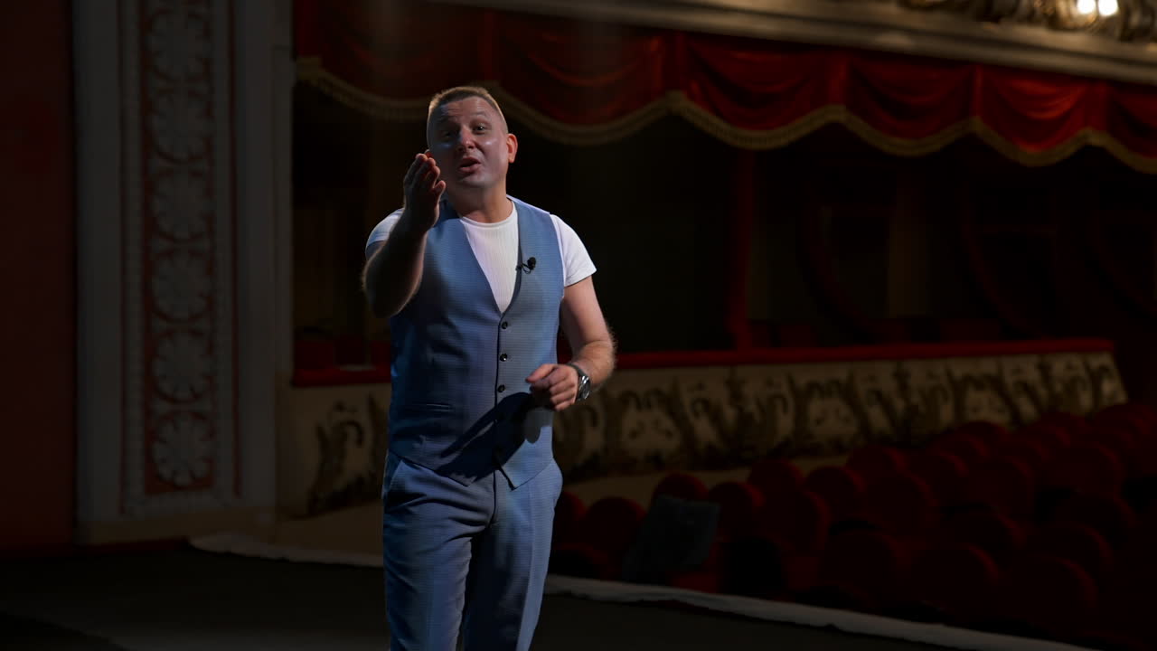 Performer points on a watch from stage and announces performances in theater. Beginning of theater season after covid-19.