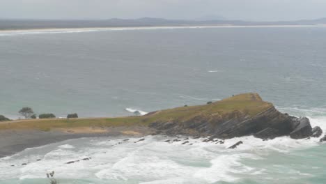niña levantando y estirando los brazos en el aire en una mañana ventosa - playa de guijarros y península en crescent head, nsw, australia