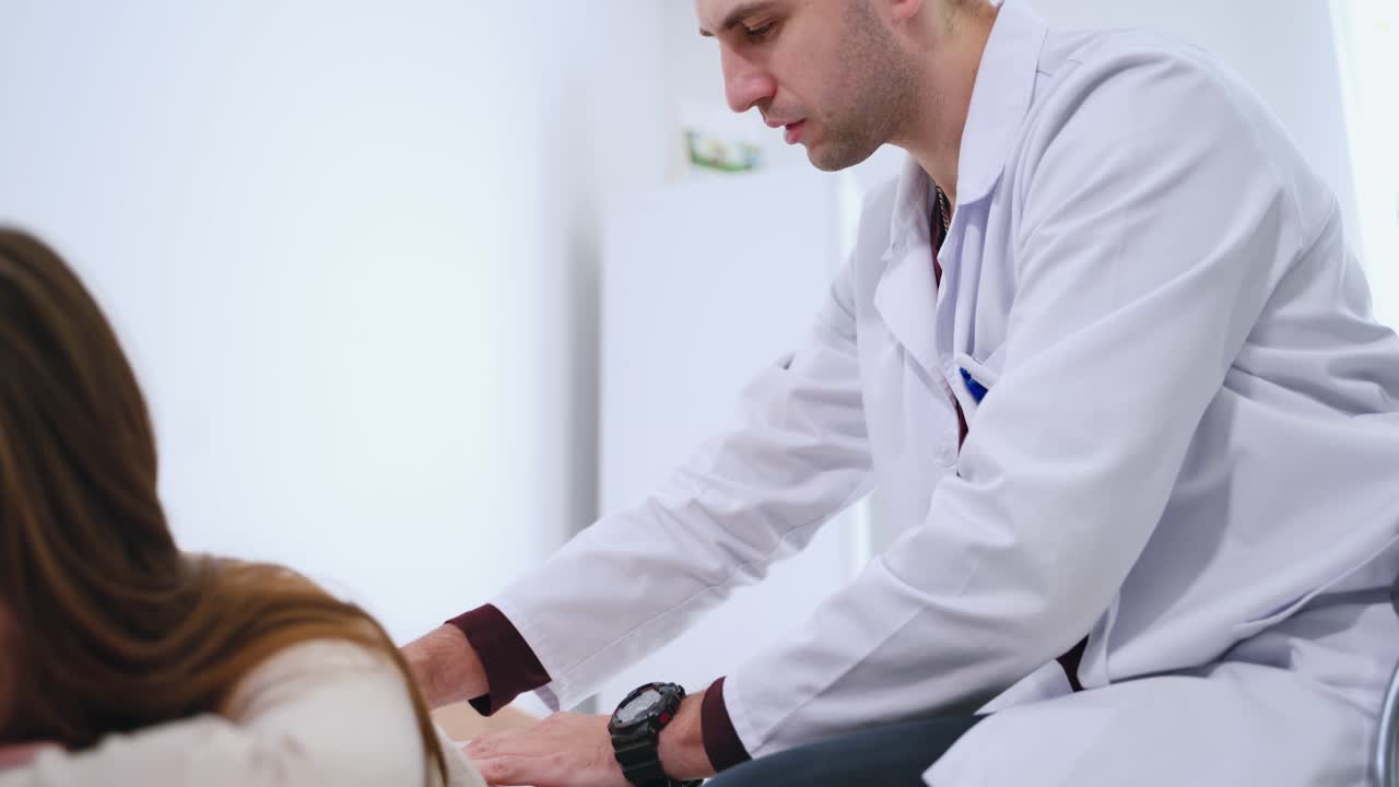 Male doctor diagnoses woman's spine. Physiotherapist is doing check up of patient's back in clinic. Female patient lying on medical bed. Health care concept.