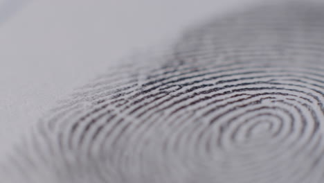 extreme close-up of fingerprint being applied to paper with camera panning