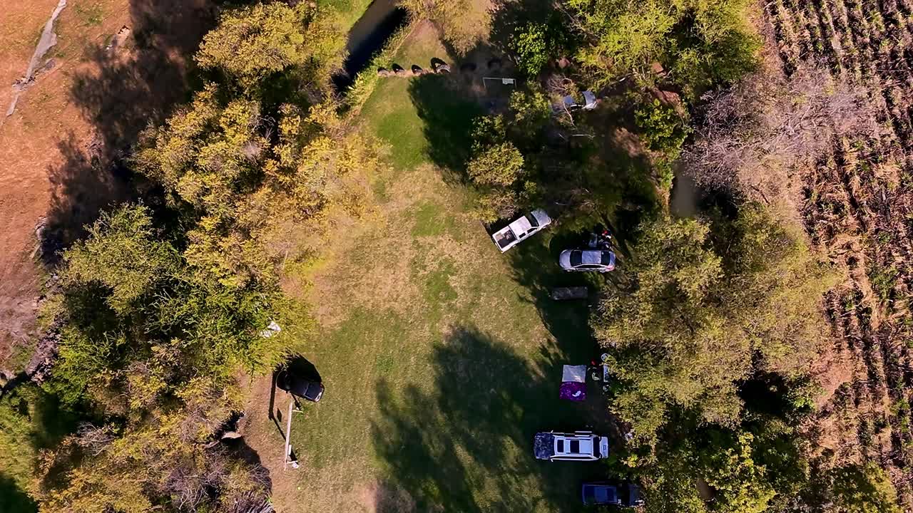 Top down drone view of Hacienda de San Jacinto Ixtoluca showing parked cars, tents and trees casting shadows in the afternoon, creating a peaceful camping atmosphere