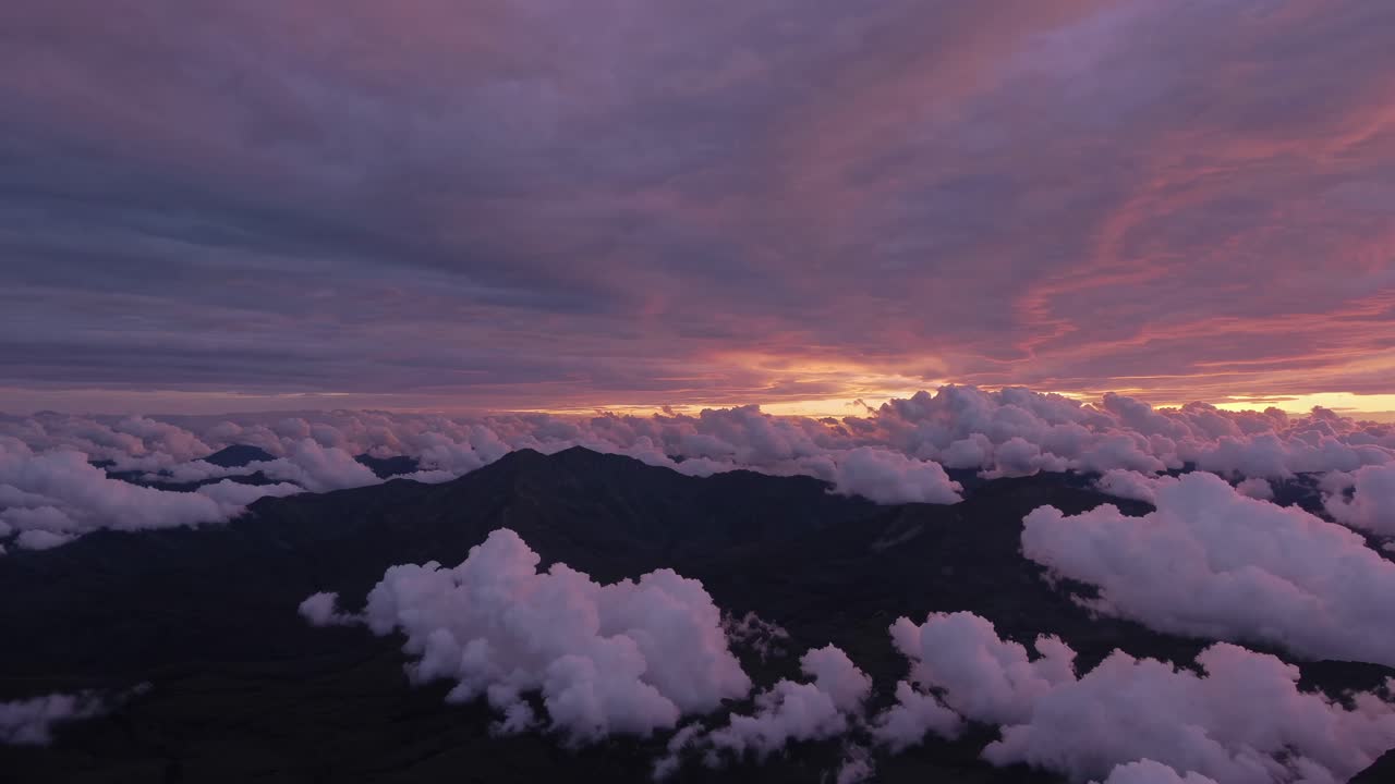 Aerial video captures a stunning sunset over mountains, with dramatic clouds and vibrant colors