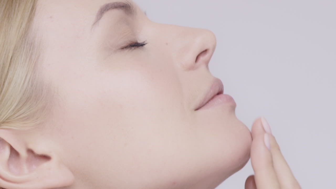 아름다운 건강한 여성이 목을 만지며 슬로우 모션으로 피부를 만지고 있습니다. 회색 바탕에 있는 미용 피부 관리 개념 빨간 서사시 드래곤