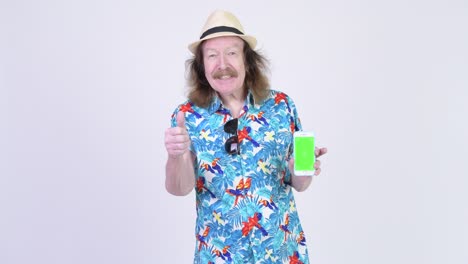 senior tourist man with mustache showing phone ready for vacation