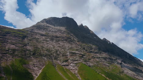 drone looking up to a mountain peak in norangsdalen, norway, with clouds making a shadow hitting the peak in summertime