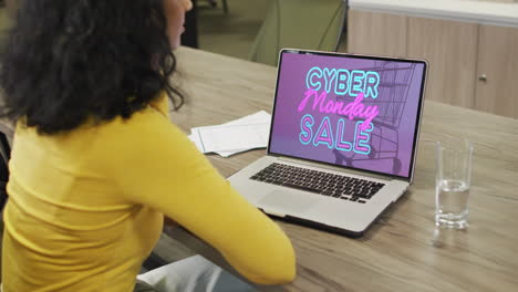 mujer biracial en la mesa usando portátil, compras en línea en el lunes cibernético, cámara lenta