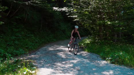 woman rides her mountain bike down a gravel mountain road on a sunny summer day