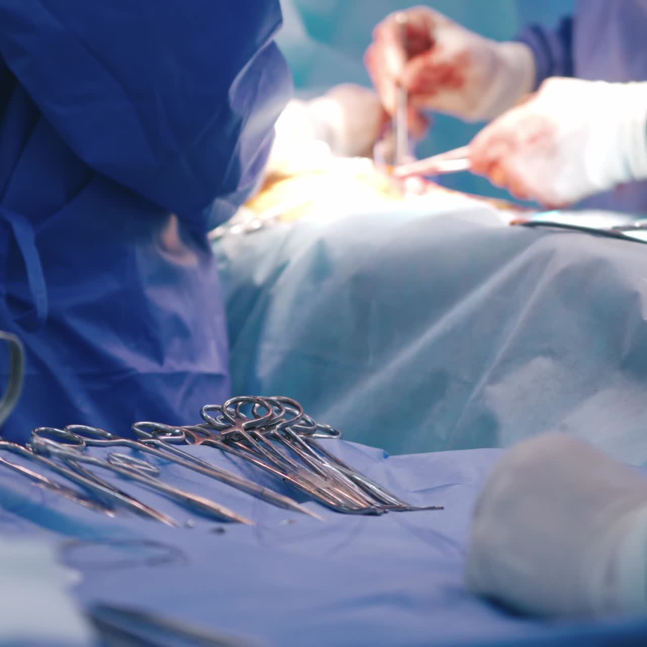 Surgical tools on the background of operation. Medical team perform operation with scissors in operating room. Surgical operation process. Medical instruments. Close-up.