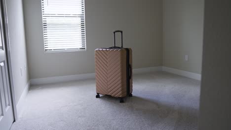 entering a sunny empty room with one bag of luggage