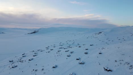 Holiday-cottages-covered-in-snow-on-a-shore-of-frozen-mountain-lake