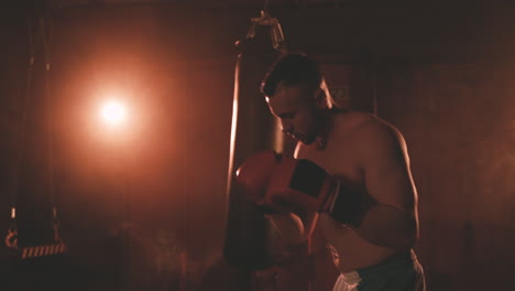 boxeador sin camisa se calienta golpeando el aire