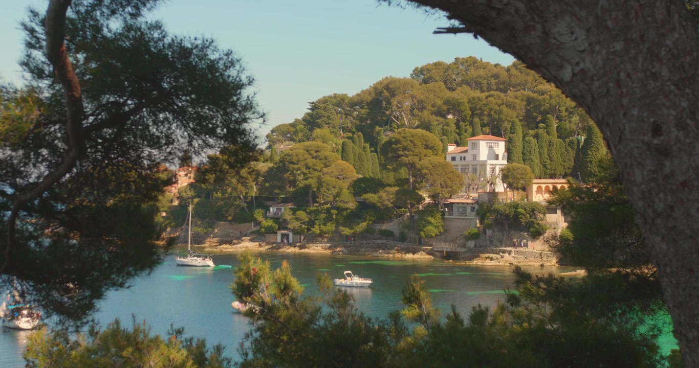 Yacht ancorati vicino a ville di lusso e vegetazione lussureggiante in una baia mediterranea soleggiata