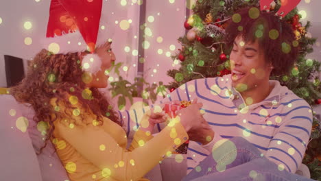 celebrating christmas, couple exchanging gifts and smiling with bokeh lights in background