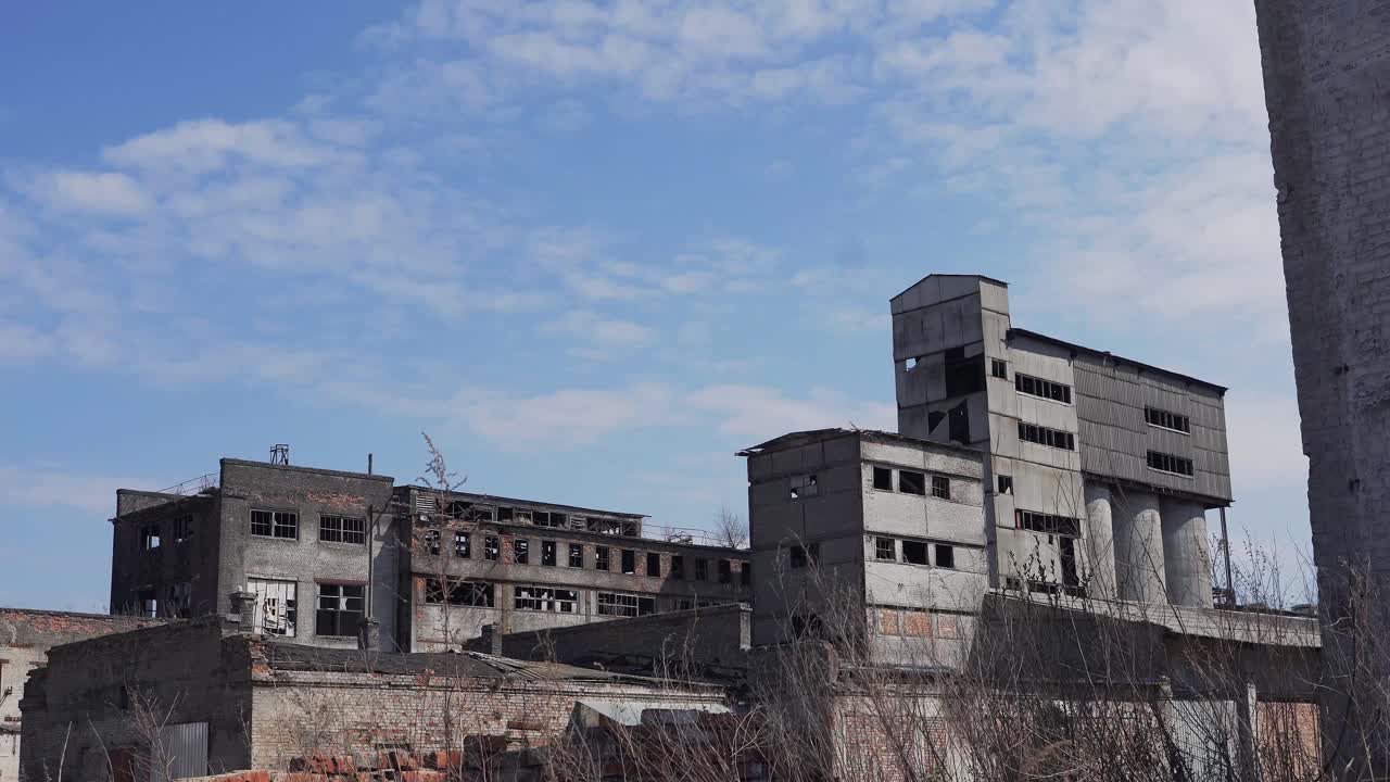 Buildings of an old ruined factory with broken windows. Brick houses, hangars, warehouses with burnt black walls