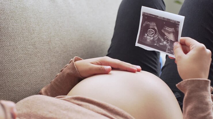 una giovane donna incinta con un'ecografia sulle mani