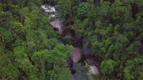 in a slow-motion aerial view, the babinda boulders in cairns, australia reveal swift creeks and dense forests intertwining with massive granite formations, offering insight into its serene name