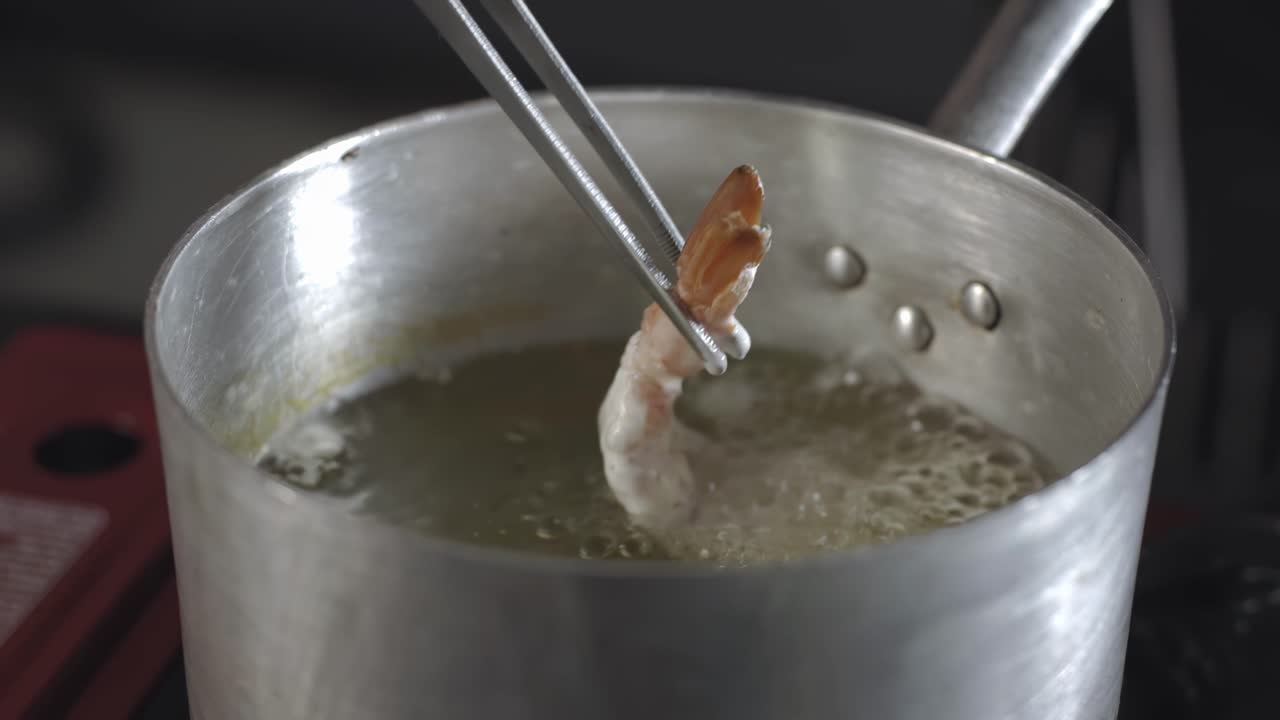 Food preparation, chef deep frying shrimp in a pot