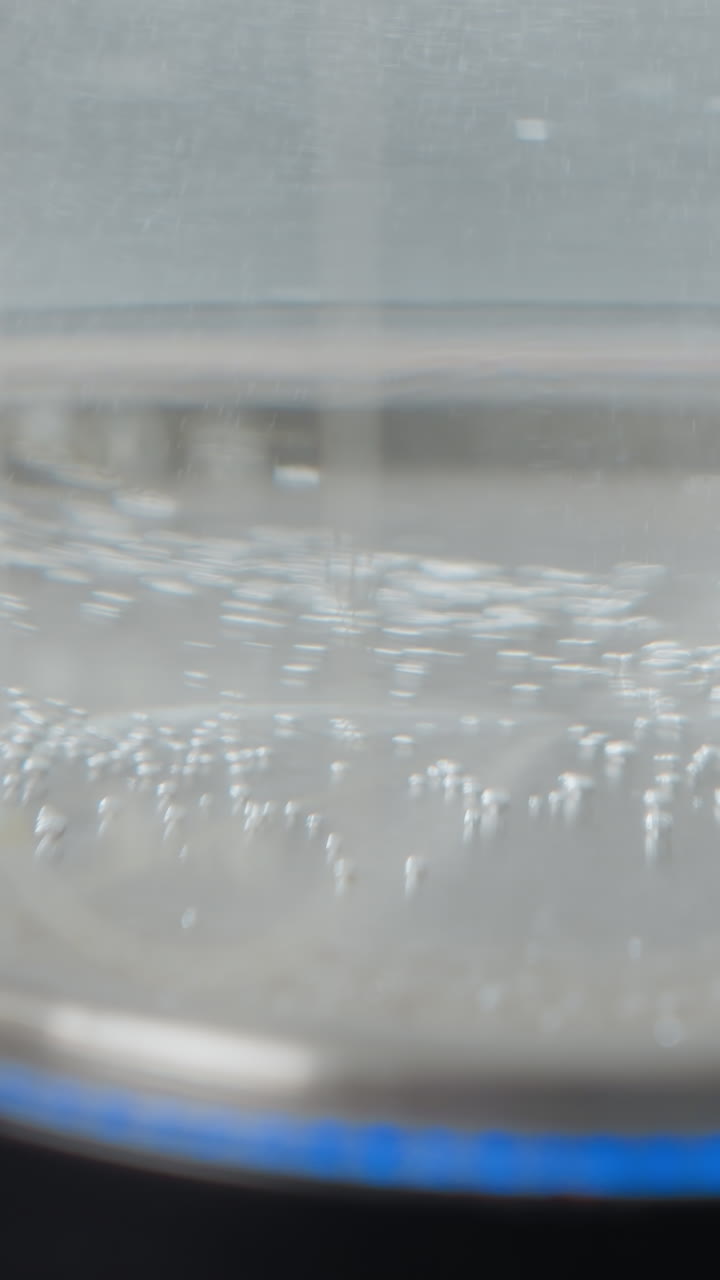 물 보일러가 뜨거워지고 거품이 상승하고 파란 빛이 박이는 클로즈업, 는 과정을 나타니다.투명한 케이틀은 는 지점에 가까워질 때 물의 움직임을 보여줍니다.