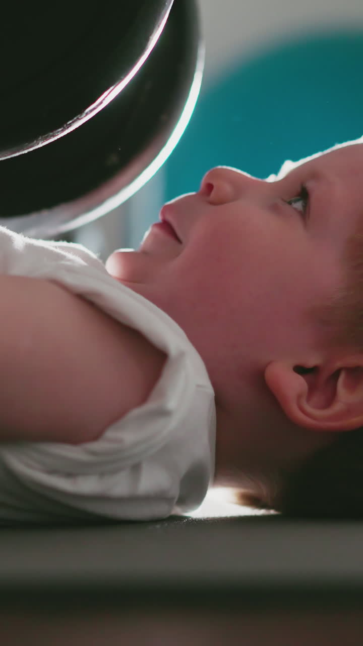 Strong little boy tries to lift heavy barbell lying on floor imitating adult in gym. Motivated kid enjoys training with weight to pump up arm muscles slow motion