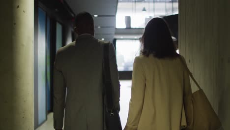 diverse businessman and businesswoman walking in lobby of modern office