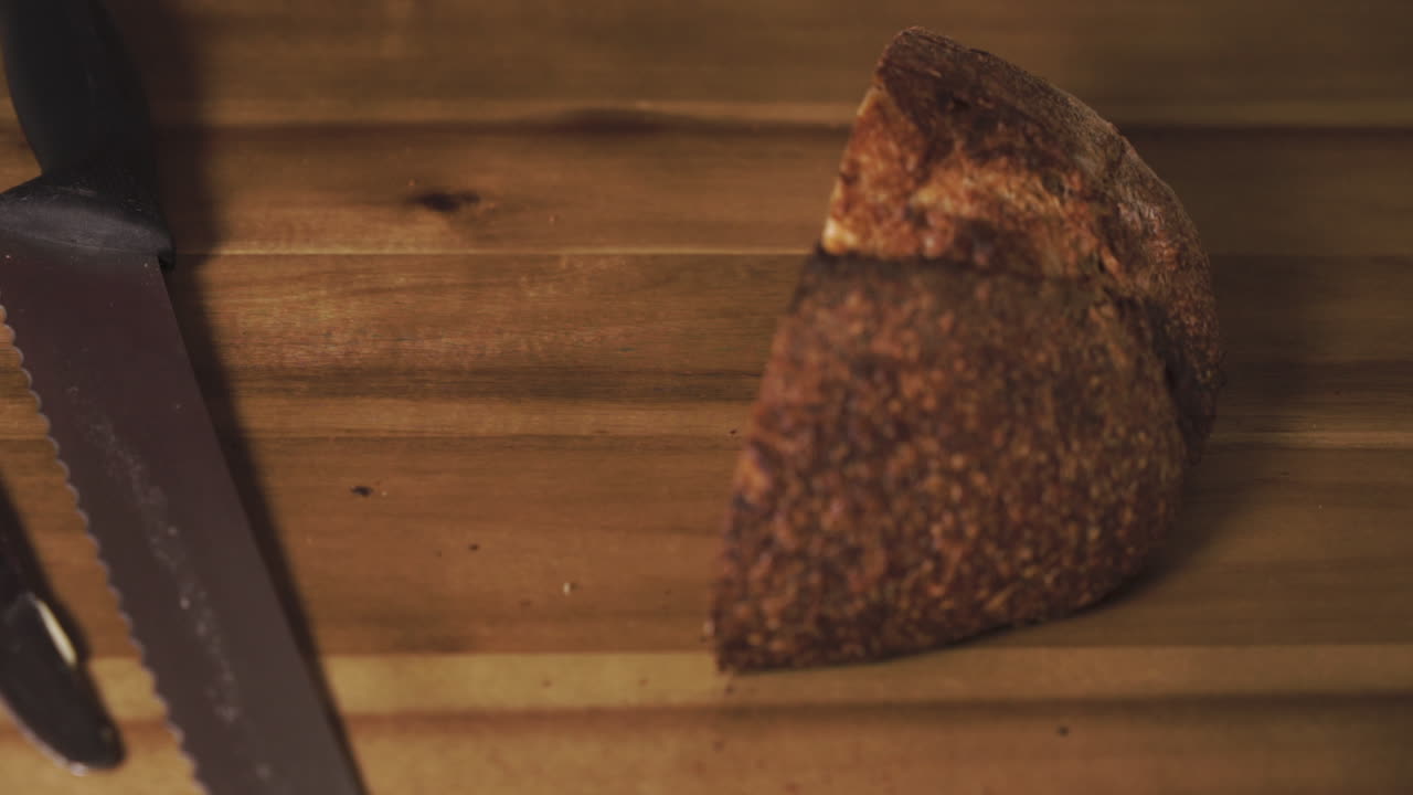 Primo piano statico di una deliziosa e gustosa fetta di pane a lievitazione naturale appena tagliata, imburrata, con un morso e riposta sul tagliere.