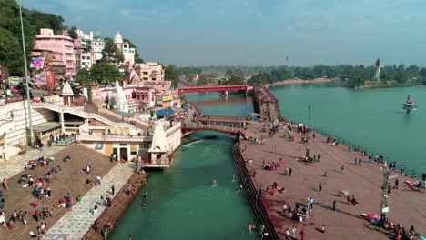 barrido aéreo delantero de har ki pauri, haridwar, uttarakhand, india mostrando ganga ghat, río sagrado ganga, peregrinos en ganga ghat y puentes sobre el río ganges