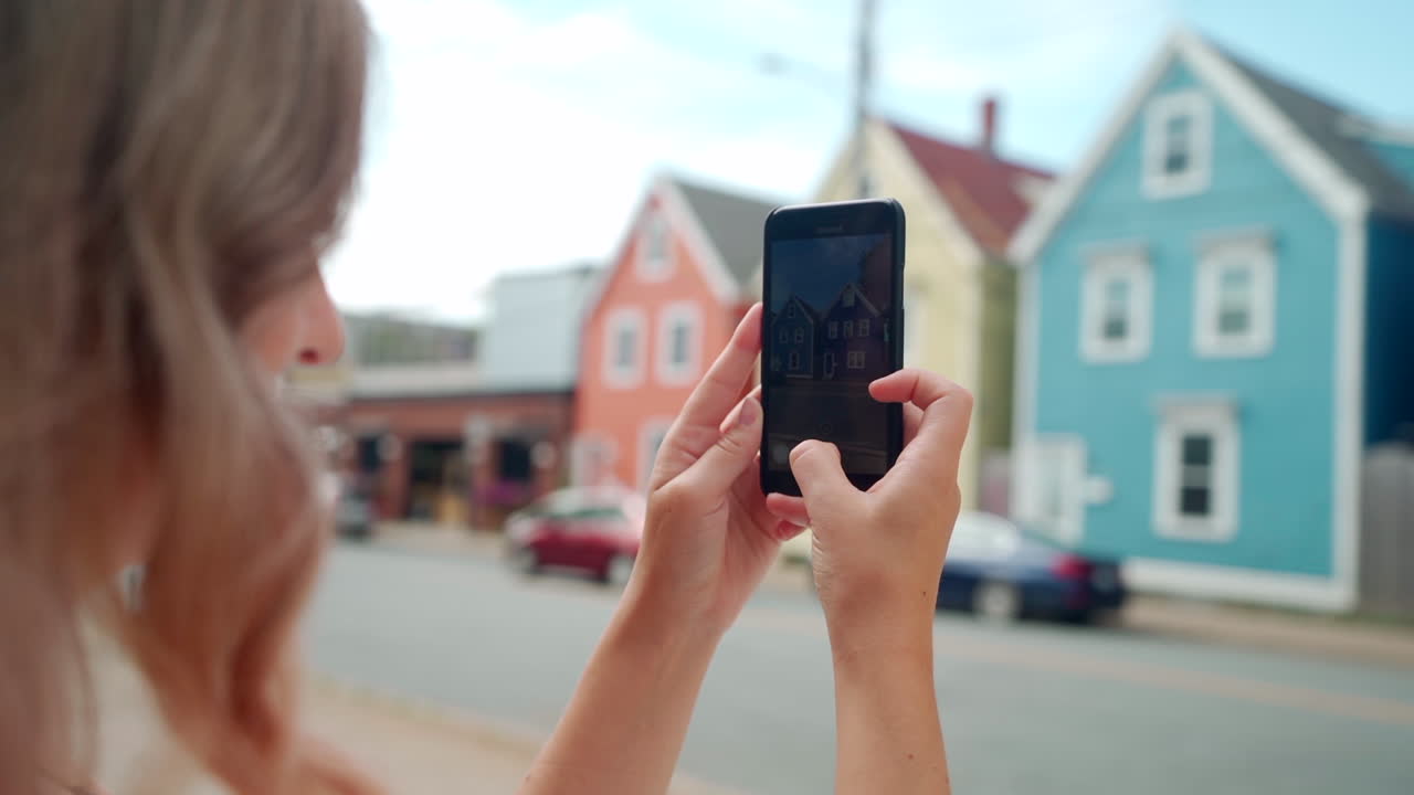 mujer tomando fotos de edificios coloridos en su teléfono celular en halifax, nueva escocia, canadá