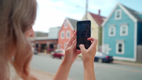 woman taking photo of colourful buildings on her cell phone in halifax, nova scotia, canada