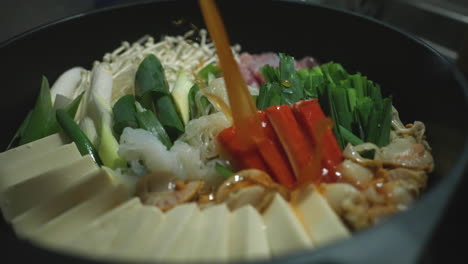 chef pouring soup stock into healthy nabe hotpot