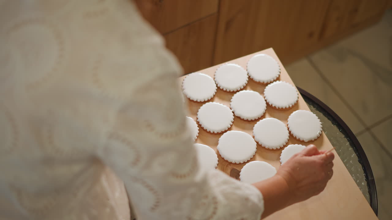 Baker arranging pumpkin pie tartlets on tray near wooden counter, closeup of hands in lace sleeve placing round pastries into liners, warm autumn lighting with powdered sugar dusting, ready for sale
