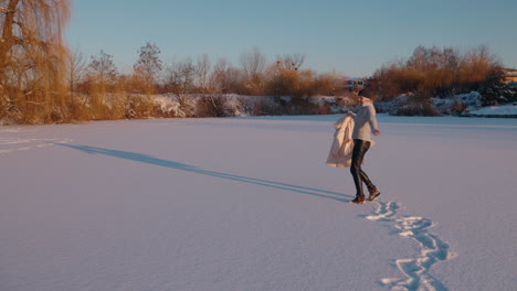 woman walking on a frozen lake at sunset