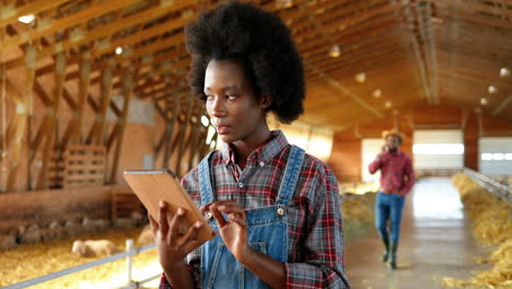 young african american woman farmer using a tablet and thinking in a stable