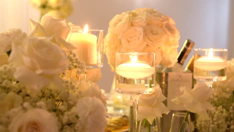 burning candle in glass container as part of table decoration with flowers