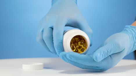 pharmacy worker pours omega fish oil capsules in hand with blue glove, slowmo