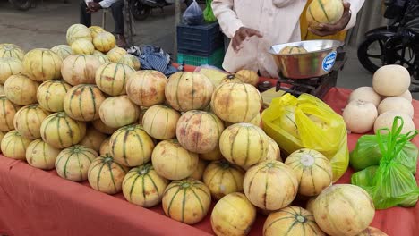 man selling muskmelon fruit in a wheelbarrow thela gaadi at roadside of india