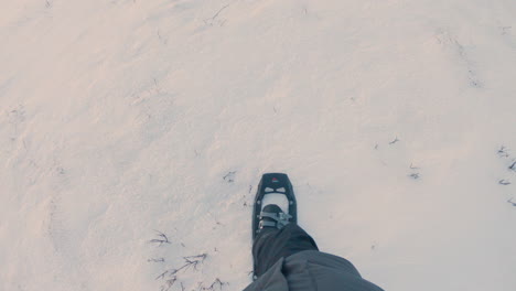 male hiker walking in deep snow with snowshoes on in slow motion