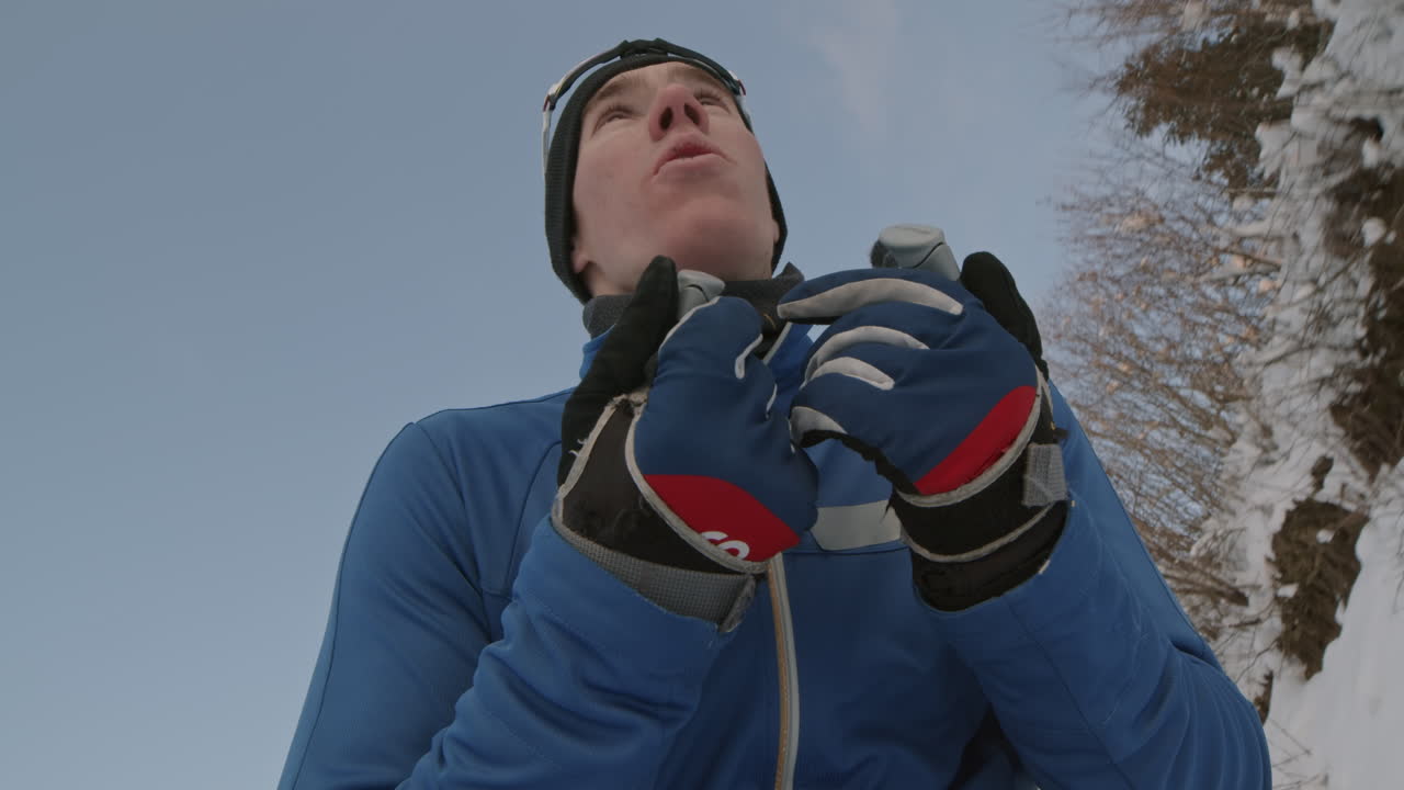 Uomo che si prepara per lo sci di fondo tra le montagne innevate