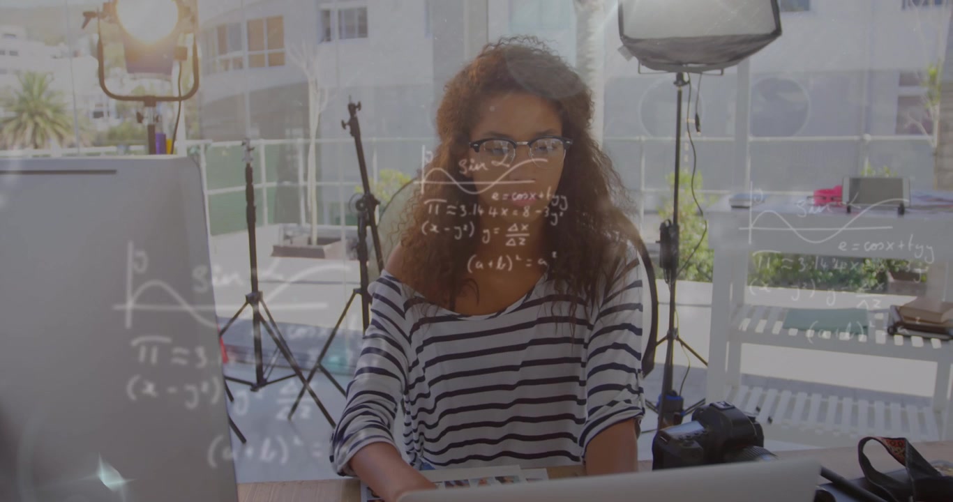 Animación de ecuaciones matemáticas sobre una empresaria afroamericana trabajando en el escritorio.
