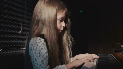 child plays synthesizer side view. pretty junior schoolgirl operates digital piano in music academy during lesson. captivating moment in artistic process