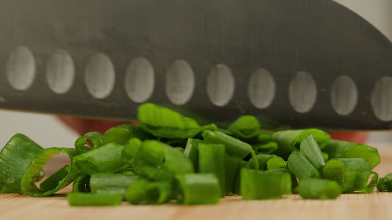 Cutting fresh green onions on a cutting board, close up chef cooking green vegan salad.