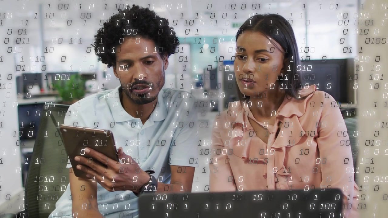 Man holding tablet showing screen, team reviewing tech data on laptop as binary overlaying scene