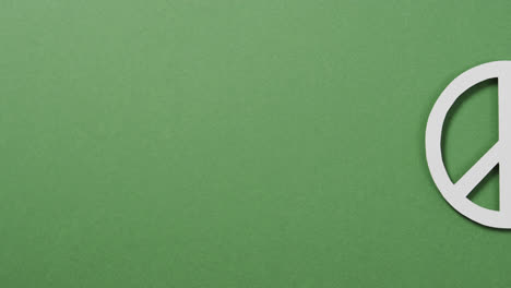 close up of white peace sign and copy space on green background