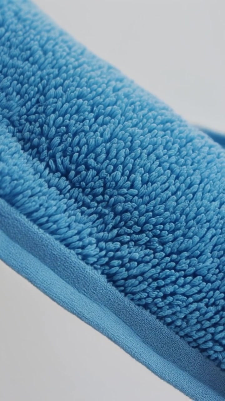 Vista macro de uma toalha esportiva azul de pelúcia mostrando laços de tecido macio e uma borda dobrada