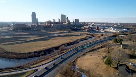 Winston-Salem-NC,-North-Carolina-zoom-in-to-skyline-with-traffic-in-foreground-aerial