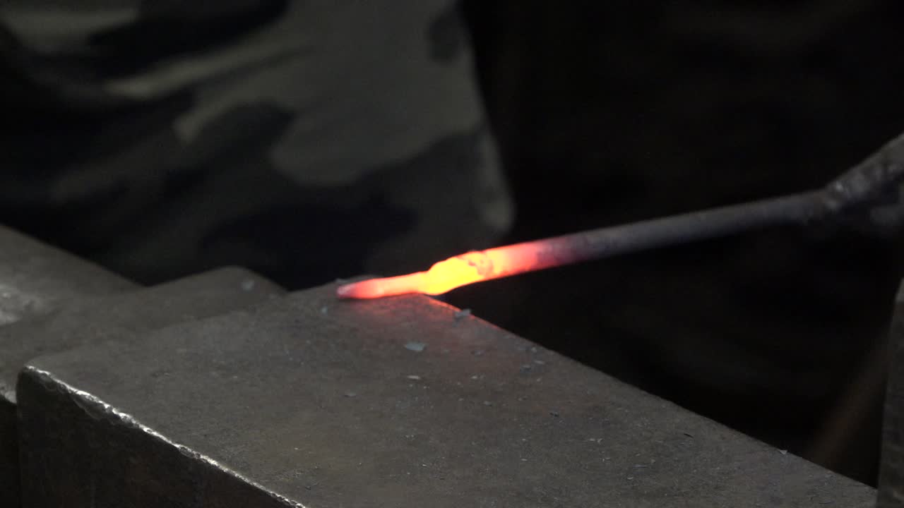 The blacksmith strikes hot metal with a hammer