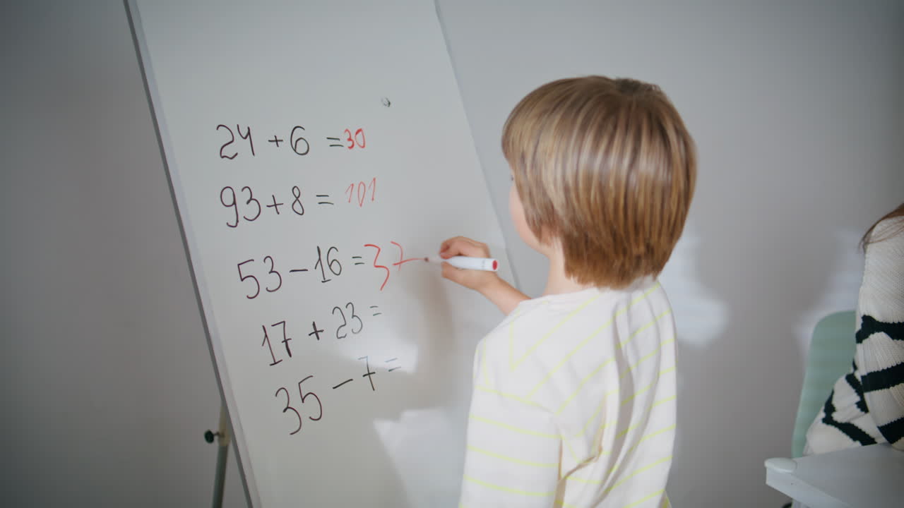 Young teacher asking boy calling board in classroom closeup. Schoolboy writing