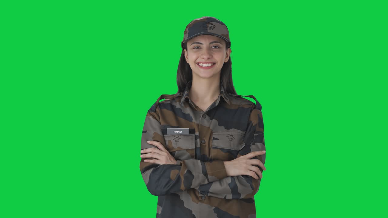Portrét šťastné indické armádní důstojnice na zeleném plátně.