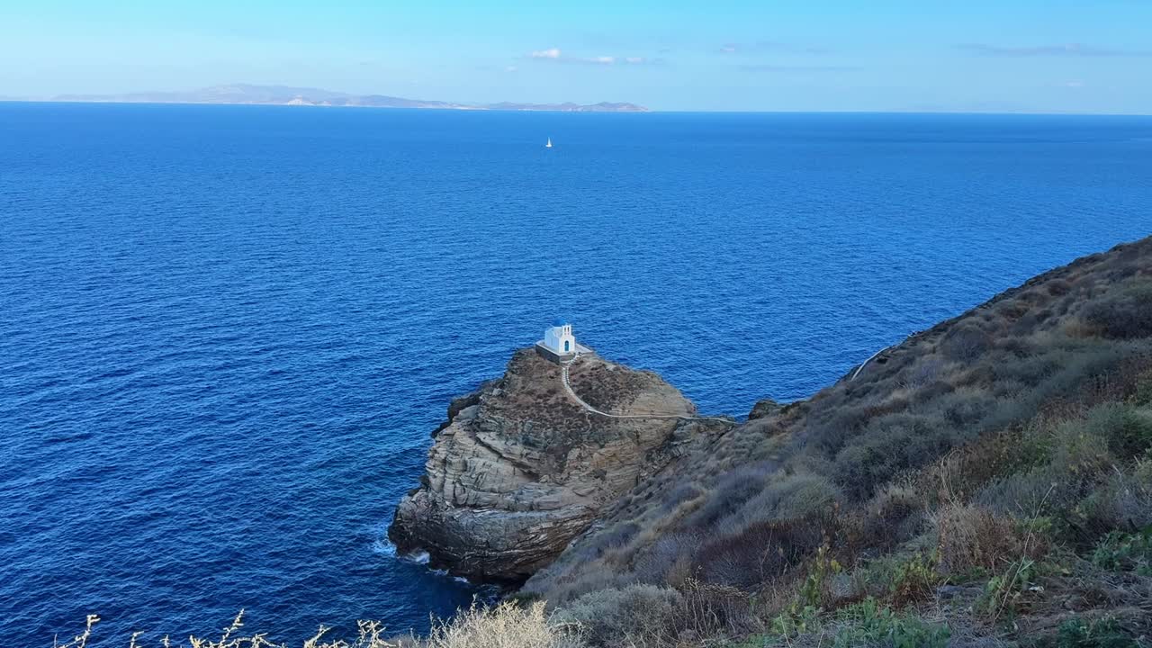 A church sits atop a rocky island, encircled by the vast, endless ocean.