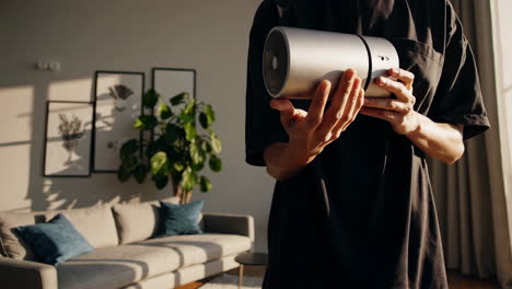 person holding a silver air purifier in a living room